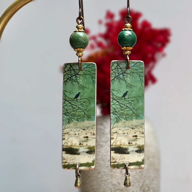 Longues boucles d'oreilles composées de pendentifs artisanaux en cuivre représentant un paysage enneigé, et de perles en chrysocolle. Pièces uniques.