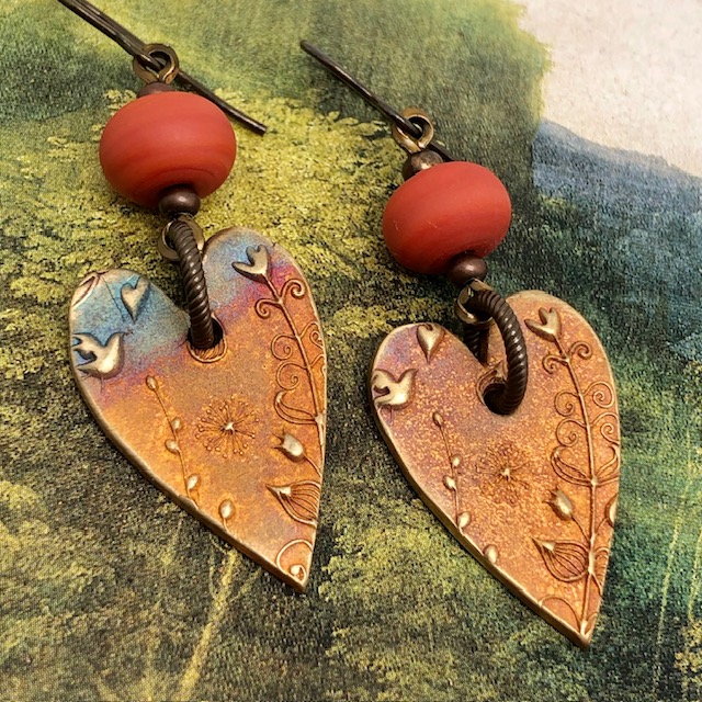 Boucles d'oreilles asymétriques coeurs terracotta composées de pendentifs en bronze et de perles lampwork. Bijoux uniques de créateur.