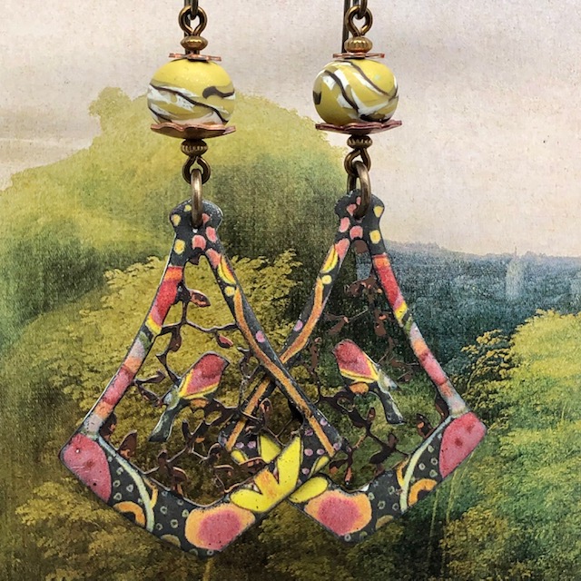 Longues d'oreilles bohèmes composées de pendentifs en cuivre émaillé ajouré qui représentent un oiseau sur une branche. Pièces uniques.