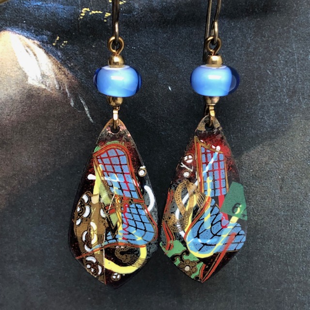 Boucles d'oreilles bleu et rouge, composées de pendentifs en cuivre émaillé au motif abstrait, composé de lignes, de quadrillages et de courbes.