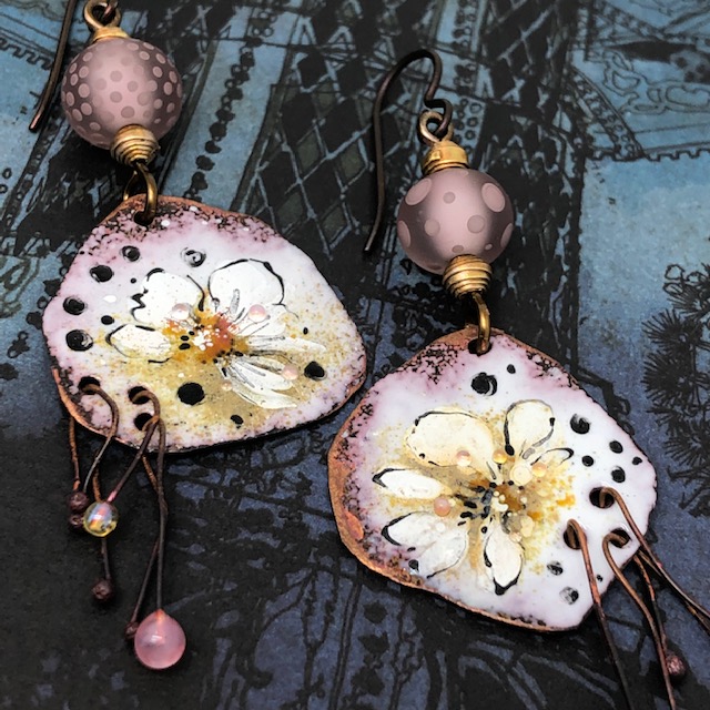 Boucles d'oreilles bohèmes asymétriques composées de pendentifs en cuivre émaillé représentant des anémones blanches. Pièces uniques.