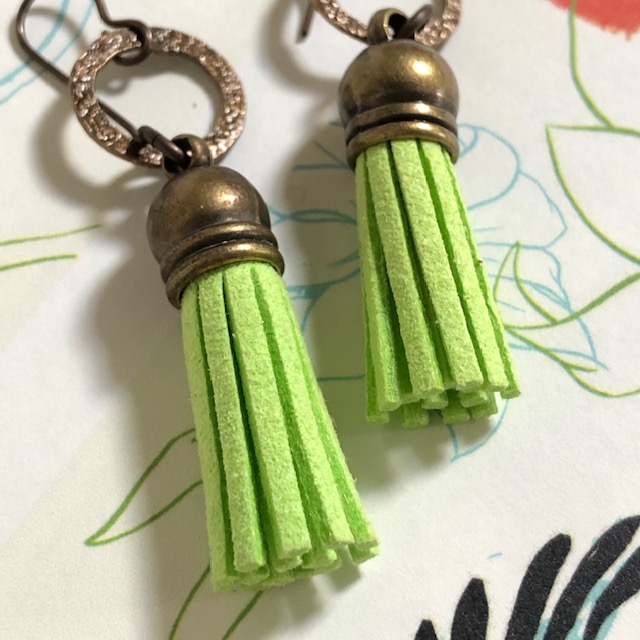 Boucles d’oreilles composées de pompons en suédine vert anis et d’anneaux en laiton. Crochets d'oreilles en laiton.