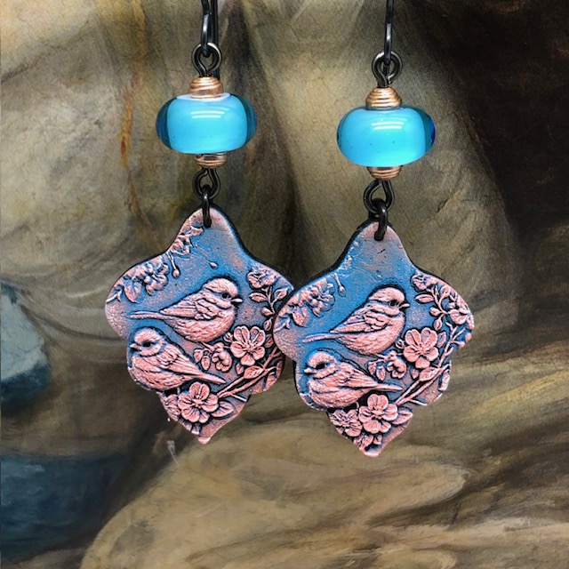 Boucles d’oreilles bohèmes composées de pendentifs en argile polymère avec un motif d'oiseau rose sur un fond bleu indigo. Bijoux uniques de créateur.