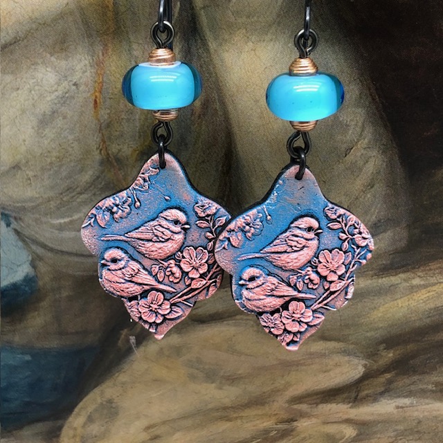 Boucles d’oreilles bohèmes composées de pendentifs en argile polymère avec un motif d'oiseau rose sur un fond bleu indigo. Bijoux uniques de créateur.