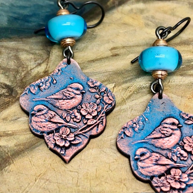 Boucles d’oreilles bohèmes composées de pendentifs en argile polymère avec un motif d'oiseau rose sur un fond bleu indigo. Bijoux uniques de créateur.