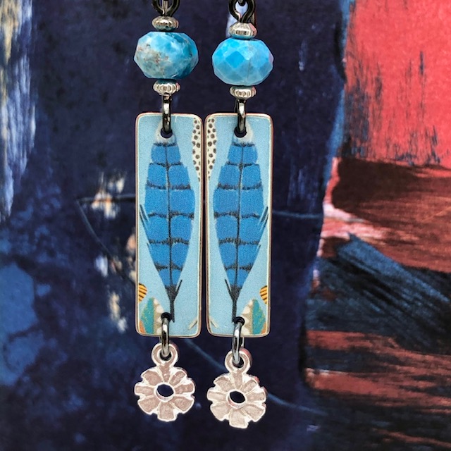 Boucles d'oreilles bohèmes composées de pendentifs artisanaux en cuivre illustré représentant des plumes d'oiseaux bleues et de perles en apatite.