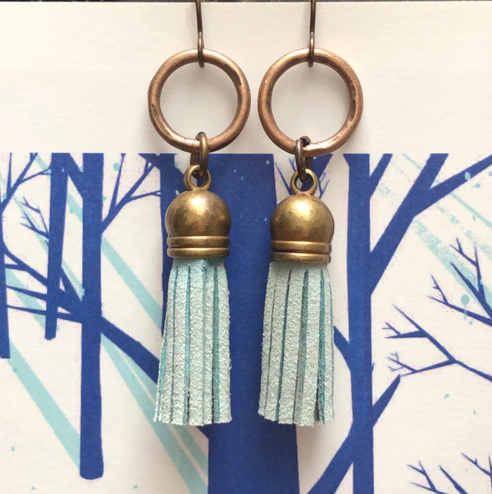 Boucles d’oreilles composées de pompons en suédine bleue et d’anneaux en laiton. Crochets d'oreilles en laiton.