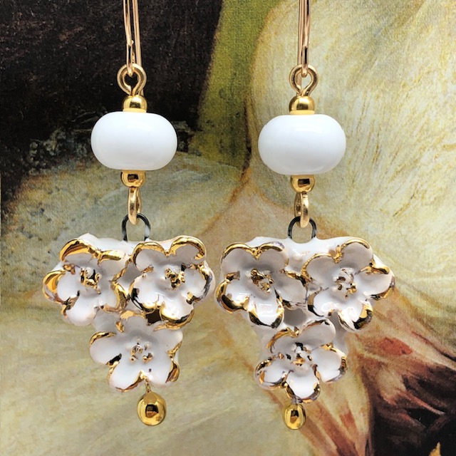 Boucles d’oreilles bohèmes composées de pendentifs en céramique qui représentent un bouquet de fleurs blanches et or. Bijoux uniques et poétiques.