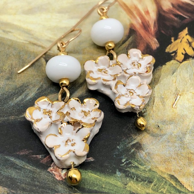 Boucles d’oreilles bohèmes composées de pendentifs en céramique qui représentent un bouquet de fleurs blanches et or. Bijoux uniques et poétiques.