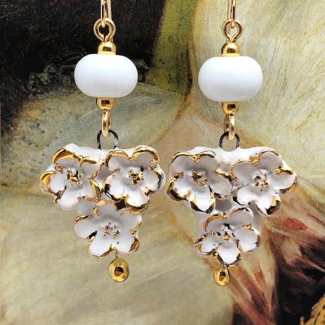 Boucles d’oreilles bohèmes composées de pendentifs en céramique qui représentent un bouquet de fleurs blanches et or. Bijoux uniques et poétiques.