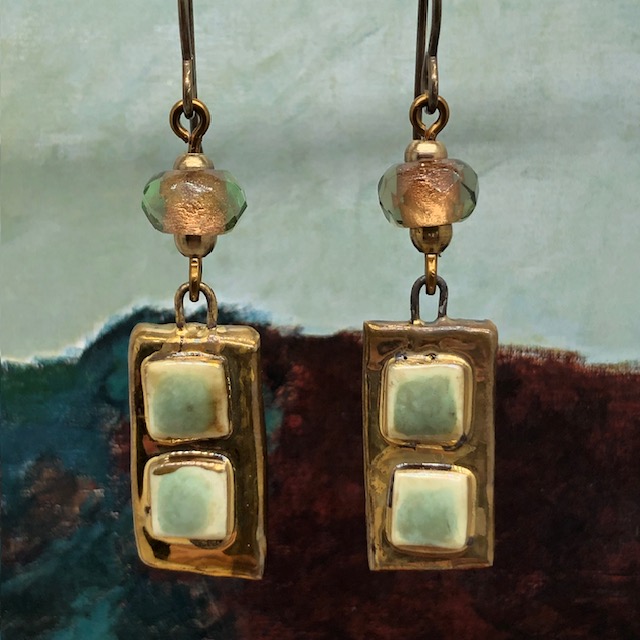 Boucles d’oreilles asymétriques composées de pendentifs artisanaux en céramique avec des carrés en relief vert amande et bronze. Bijoux uniques.