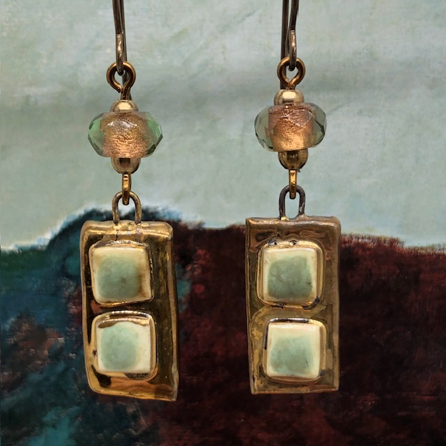 Boucles d’oreilles asymétriques composées de pendentifs artisanaux en céramique avec des carrés en relief vert amande et bronze. Bijoux uniques.