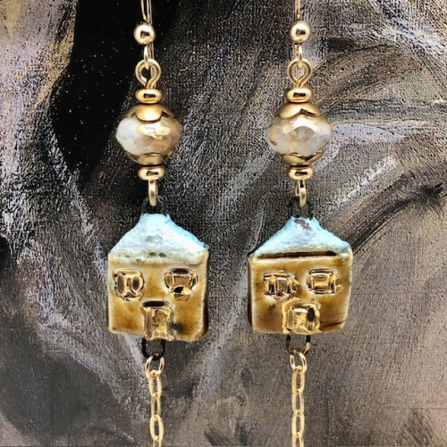 Boucles d’oreilles poétiques composées de pendentifs en céramique dorés en forme de petit chalet sous la neige. Bijoux uniques de créateur.
