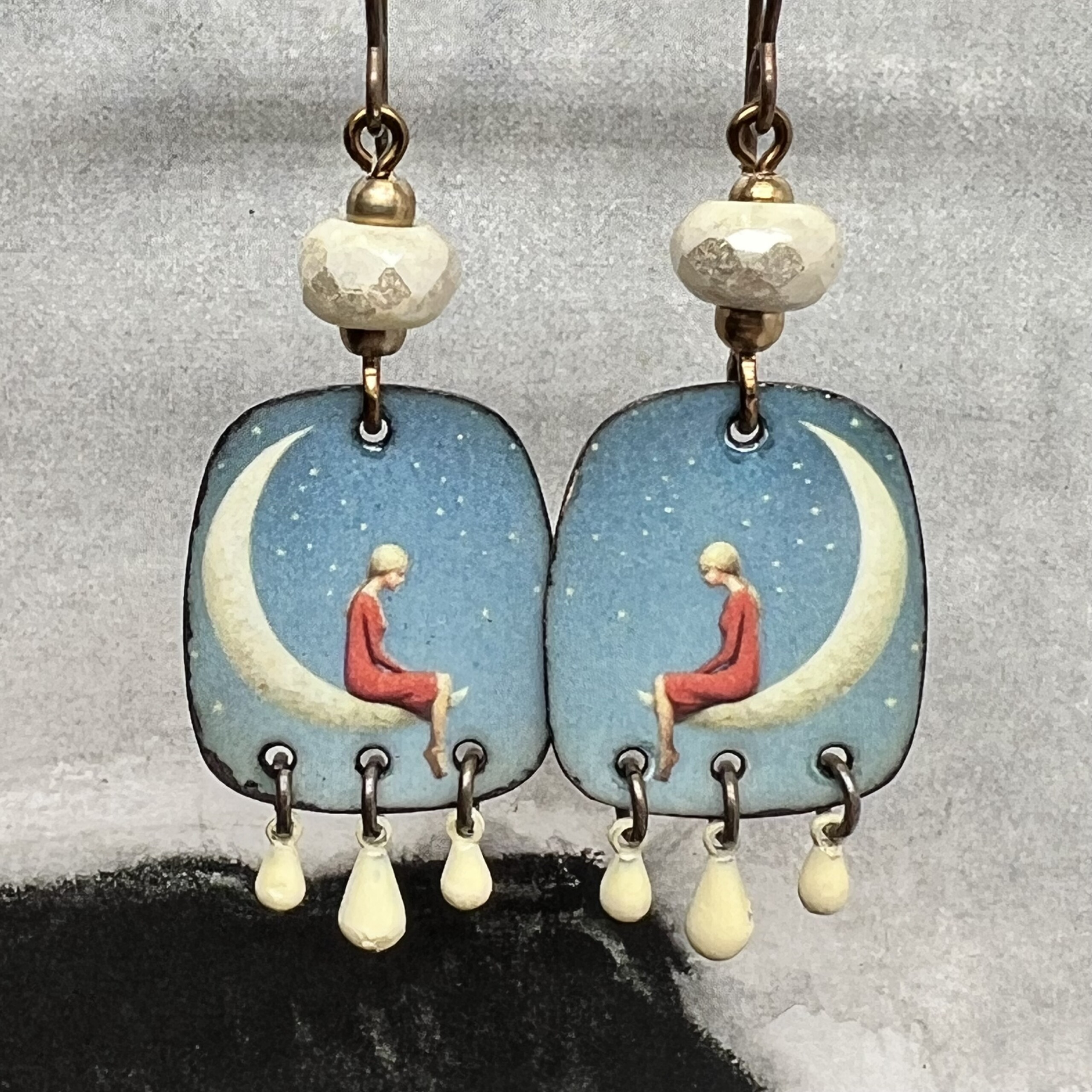 Boucles d’oreilles poétiques composées de pendentifs en cuivre émaillé avec le portrait d'une jeune fille assise sur un croissant de lune. Bijoux uniques.