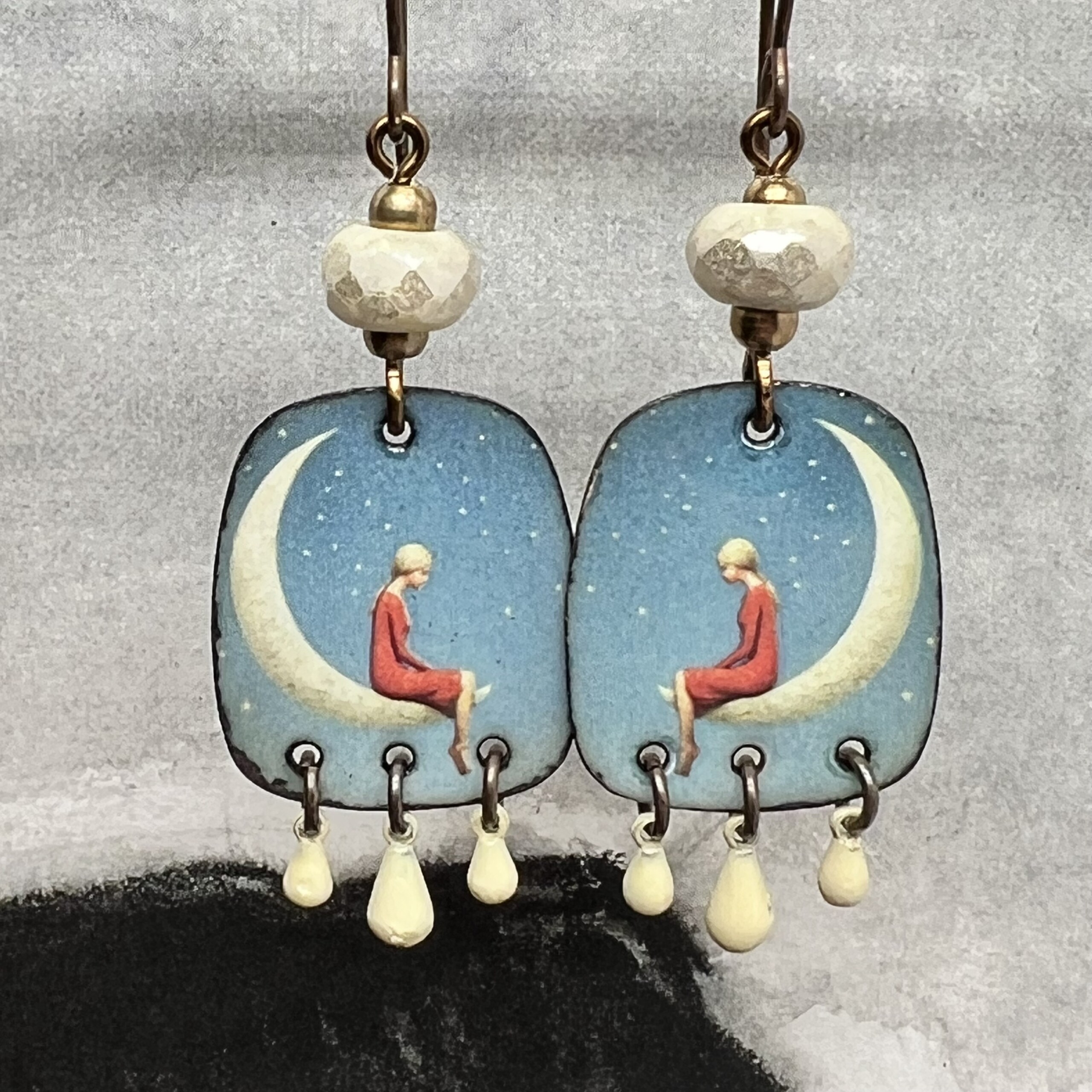 Boucles d’oreilles poétiques composées de pendentifs en cuivre émaillé avec le portrait d'une jeune fille assise sur un croissant de lune. Bijoux uniques.