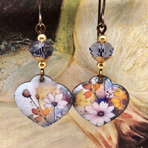 Boucles d'oreilles asymétriques bohèmes composées de pendentifs en cuivre émaillé en forme de coeur, avec un motif de fleurs parme. Bijoux uniques.