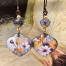 Boucles d'oreilles asymétriques bohèmes composées de pendentifs en cuivre émaillé en forme de coeur, avec un motif de fleurs parme. Bijoux uniques.