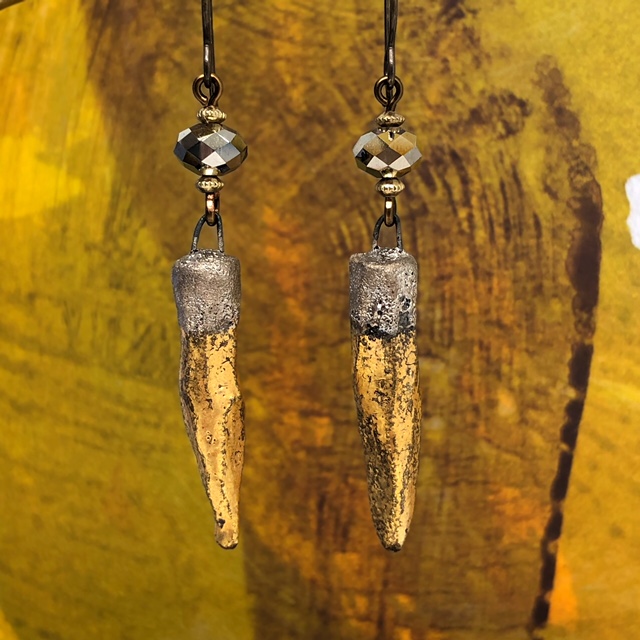 Longues boucles d'oreilles composées de pendentifs artisanaux en céramique en forme de cônes or et argent. Pièces uniques.