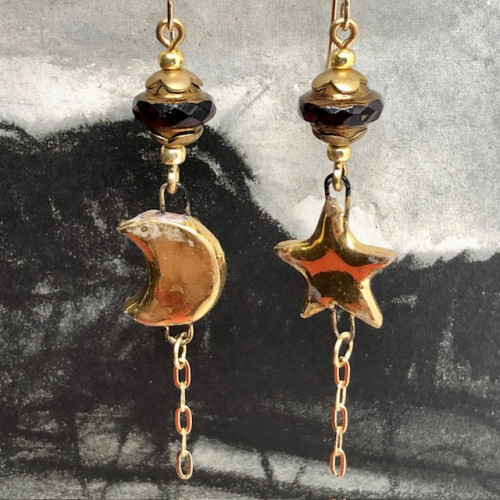 Longues boucles d'oreilles asymétriques étoile et lune, composées de pendentifs en céramique dorée et chocolat. Bijoux uniques de créateur.