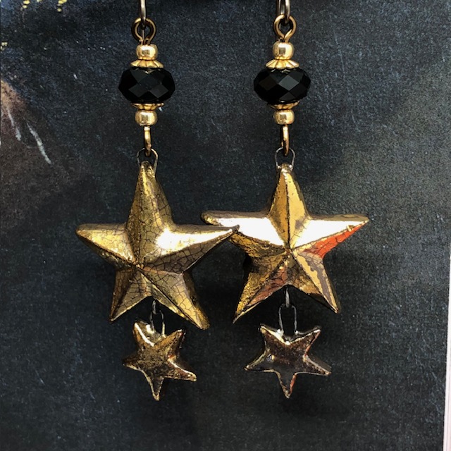 Boucles d'oreilles bohèmes composées de pendentifs en céramique en forme d'étoiles dorées et de perles en cristal Swarovski noires. Bijoux uniques.