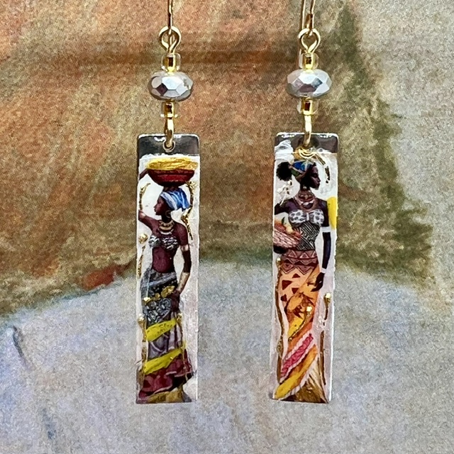 Longues boucles d’oreilles composées de pendentifs en laiton émaillé avec le portrait de femmes africaines porteuses. Bijoux uniques de créateur.