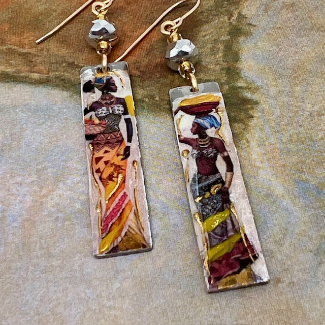 Longues boucles d’oreilles composées de pendentifs en laiton émaillé avec le portrait de femmes africaines porteuses. Bijoux uniques de créateur.