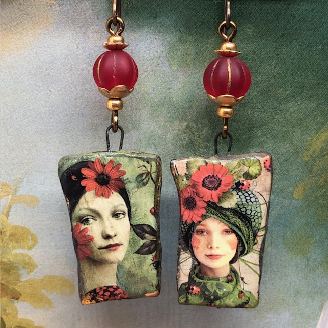 Boucles d’oreilles bohèmes asymétriques composées de pendentifs en céramique avec un portrait de femme aux cheveux piqués de fleurs rouges. Bijoux uniques.