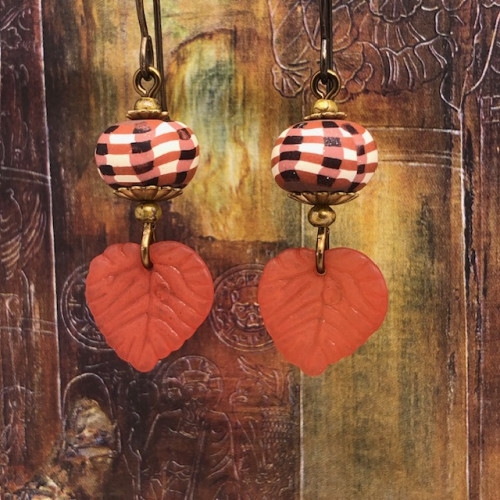 Petites boucles d’oreilles bohèmes composées de feuilles en acrylique orange cuivré et de perles en argile polymère multicolores. Bijoux uniques.