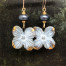 Boucles d’oreilles bohèmes asymétriques composées de pendentifs en céramique en forme de fleur blanche, grise et or. Bijoux uniques de créateur.