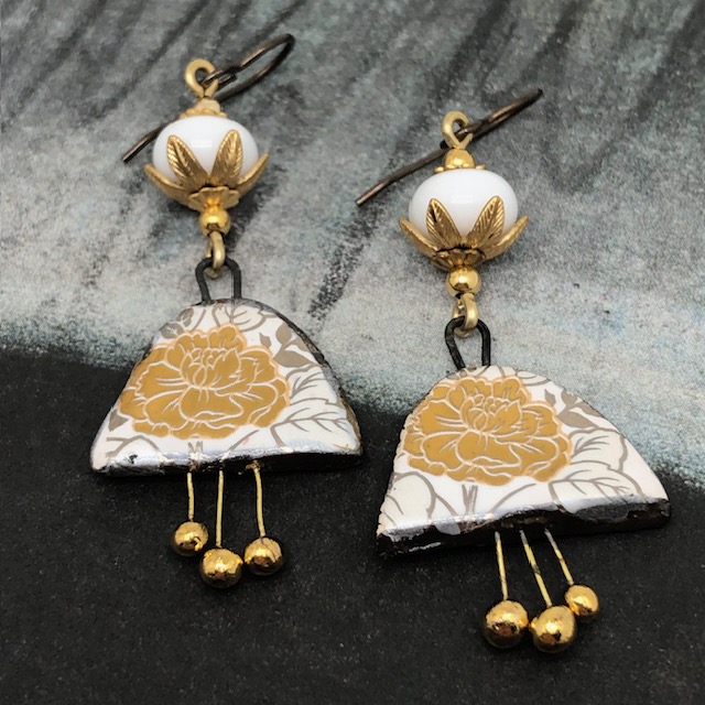Boucles d'oreilles bohèmes composées de pendentifs en céramique avec un motif de fleurs dorées au feuillage argenté. Bijoux uniques de créateur.