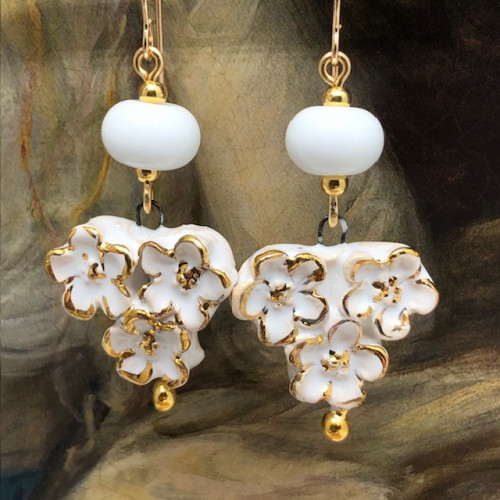 Boucles d’oreilles bohèmes composées de pendentifs en céramique qui représentent un bouquet de fleurs blanches et or. Bijoux uniques et poétiques.