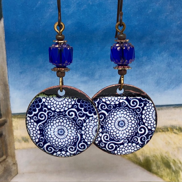 Boucles d'oreilles bohèmes composées de pendentifs en cuivre émaillé représentant des dahlias bancs sur un fond bleu marine. Modèle unique.