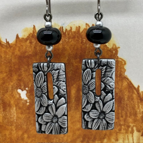 Boucles d’oreilles asymétriques bohèmes composées de pendentifs en argile polymère avec un motif floral gris argenté. Bijoux uniques de créateur.