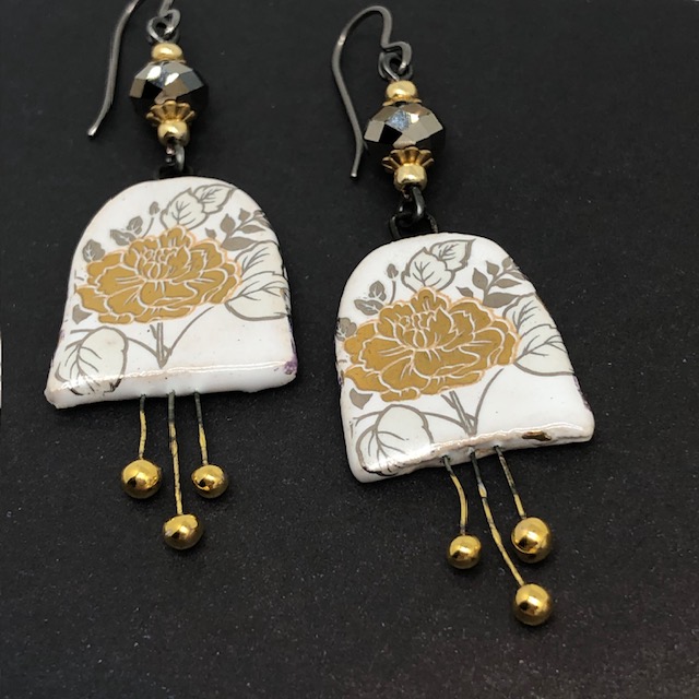 Longues boucles d'oreilles bohèmes composées de pendentifs en céramique avec un motif de fleurs dorées au feuillage argenté. Bijoux uniques.