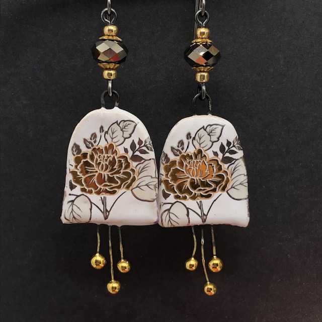 Longues boucles d'oreilles bohèmes composées de pendentifs en céramique avec un motif de fleurs dorées au feuillage argenté. Bijoux uniques.