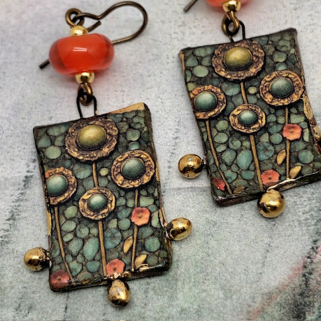 Grandes boucles d'oreilles bohèmes composées de pendentifs en céramique avec des fleurs vert kaki et orange vif. Bijoux uniques de créateur.