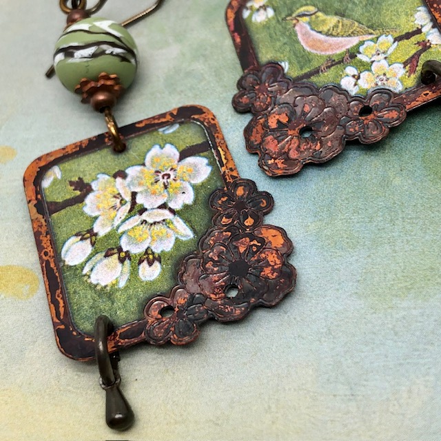 Boucles d'oreilles asymétriques vintage composées de pendentifs en cuivre avec un oiseau et un motif de fleurs de cerisier. Bijoux uniques de créateur.