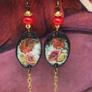 Boucles d'oreilles bohème composées de pendentifs en cuivre émaillé représentant une fleur rouge et un oiseau mauve, sur un décor parsemé de touches d'or.