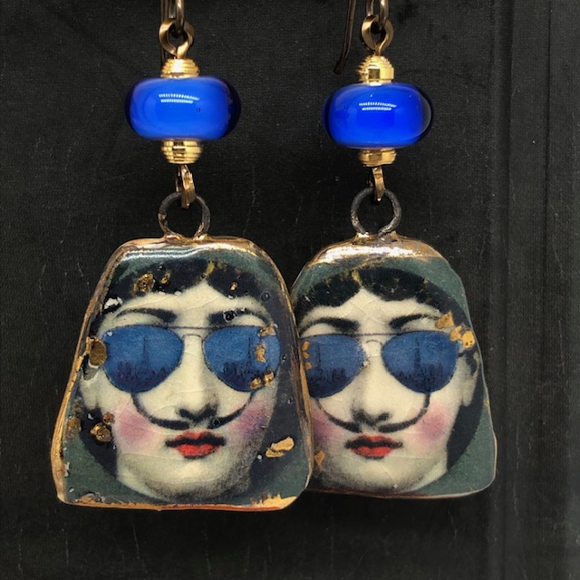 Boucles d'oreilles en céramique représentant Lina Cavalieri, dessinée par Fornasetti, avec les moustaches de Dali et une paire de lunettes bleu.