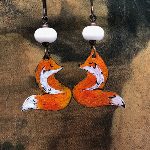 Boucles d’oreilles asymétriques composées de pendentifs en cuivre émaillé représentant un renard roux et blanc. Bijoux uniques de créateur.