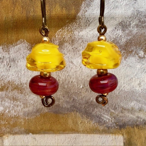 Boucles d'oreilles bohèmes composées de perles en verre filé à la flamme rouges et jaunes avec une forme irrégulière. Bijoux uniques de créateur.