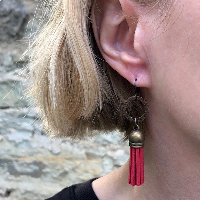 Boucles d’oreilles composées de pompons en suédine rouge et surmontées d’anneaux en laiton. Crochets d'oreilles en laiton.