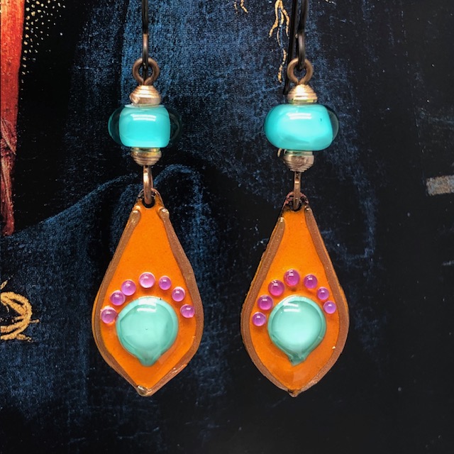 Boucles d'oreilles Pop composées de pendentifs artisanaux en cuivre émaillé orange vif avec des picots roses et bleu turquoise. Bijoux uniques.