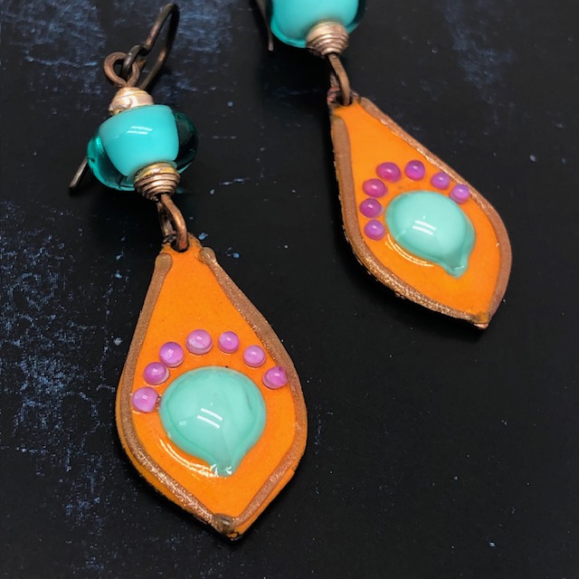 Boucles d'oreilles Pop composées de pendentifs artisanaux en cuivre émaillé orange vif avec des picots roses et bleu turquoise. Bijoux uniques.