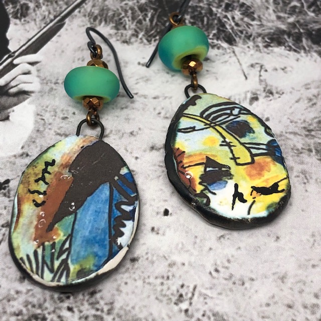 Boucles d'oreilles graffitis composées de pendentifs artisanaux en céramique aux couleurs minérales et de perles en verre filé vert lagon.