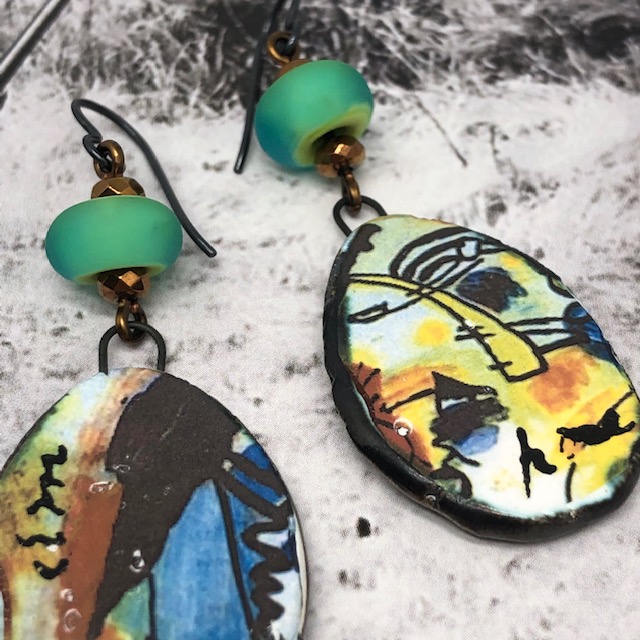 Boucles d'oreilles graffitis composées de pendentifs artisanaux en céramique aux couleurs minérales et de perles en verre filé vert lagon.