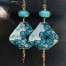 Grandes boucles d'oreilles bohèmes asymétriques composées de pendentifs en cuivre émaillé avec un motif de fleurs bleues turquoise. Bijoux uniques.
