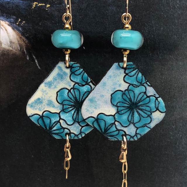 Grandes boucles d'oreilles bohèmes asymétriques composées de pendentifs en cuivre émaillé avec un motif de fleurs bleues turquoise. Bijoux uniques.