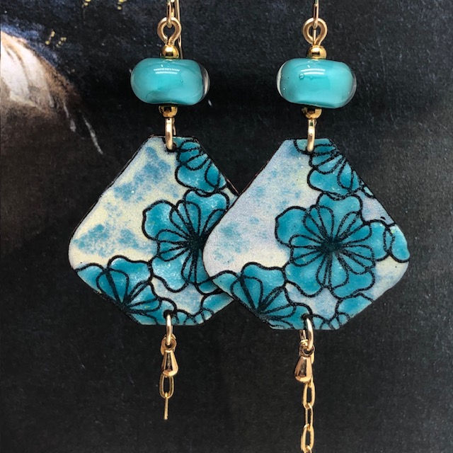 Grandes boucles d'oreilles bohèmes asymétriques composées de pendentifs en cuivre émaillé avec un motif de fleurs bleues turquoise. Bijoux uniques.