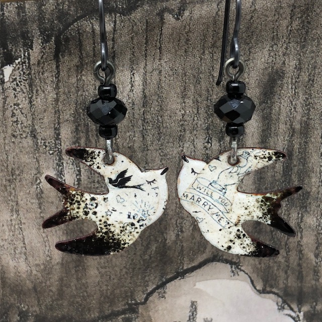 Petites boucles d'oreilles asymétriques et poétiques composées de pendentifs en cuivre émaillé, en forme d'hirondelle. Bijoux uniques de créateur.